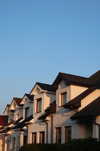 A row of white houses with dark roofs under a clear blue evening sky