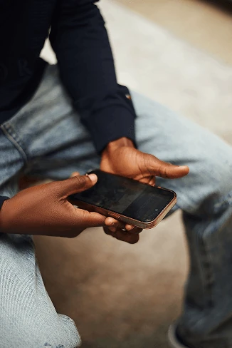 A person sitting with a phone held in both hands